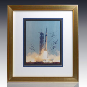 Framed photo of Saturn V rocket launch signed by astronauts.